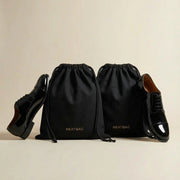 Black drawstring bags with shoes on a beige background, featuring the brand 'NEATBAG'.